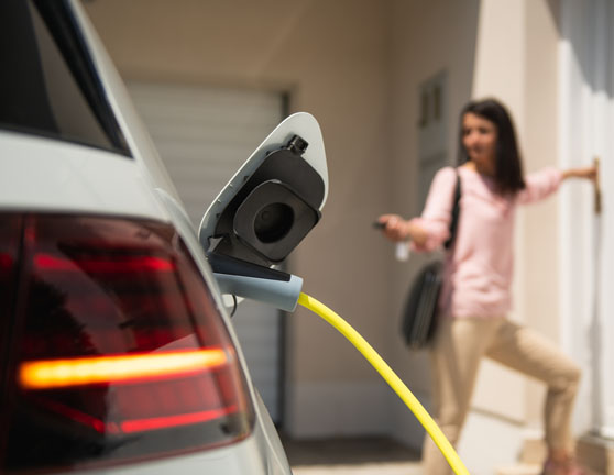 Mujer cerrando un coche eléctrico mientras carga