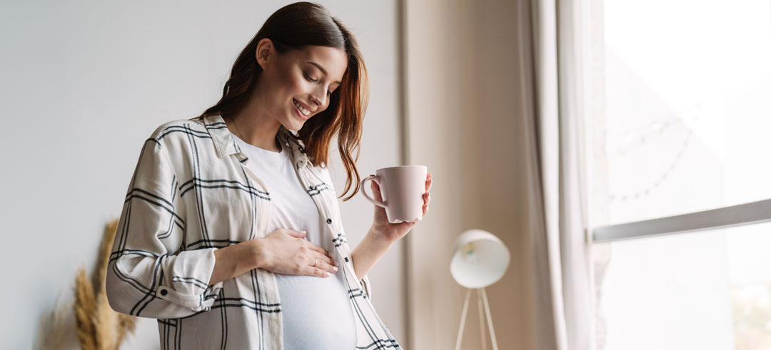 Mujer embarazada tocándose la barriga en una habitación
