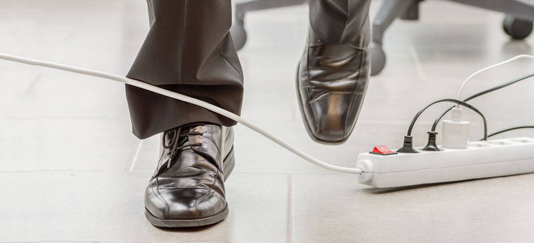 Persona andando y cruzándose con un cable de una regleta