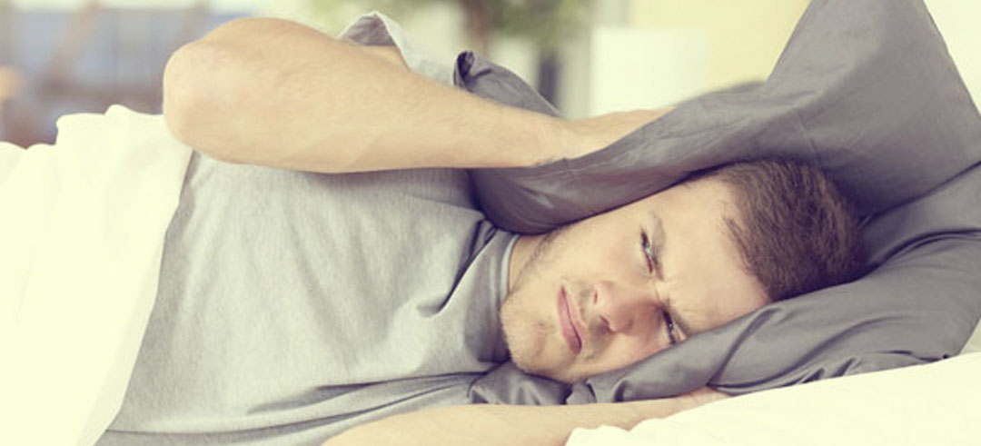 Persona molesta tapándose los oídos con la almohada